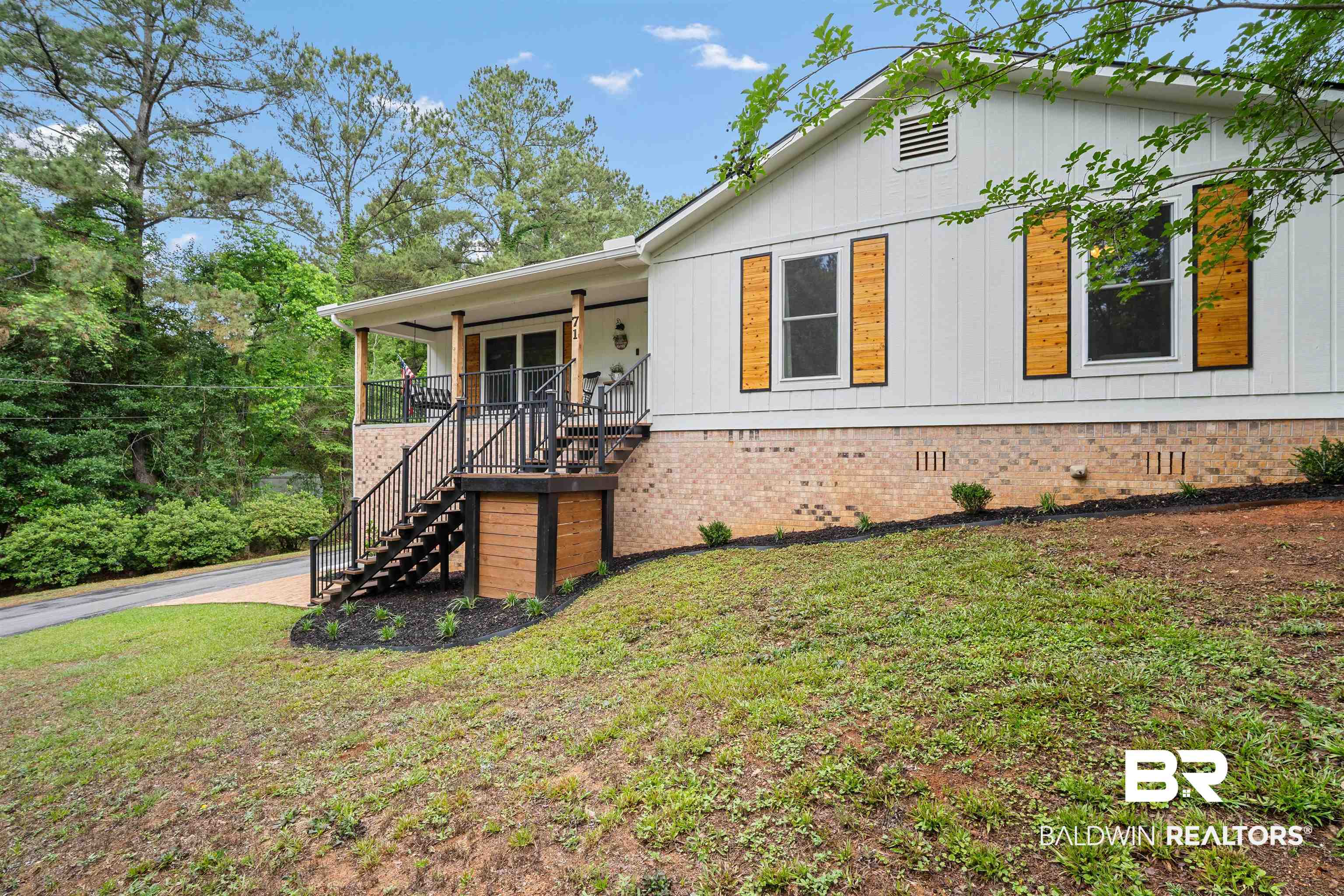 71 Caisson Trace Daphne, AL 36527 - Photo 3 of 36 White siding exterior with a brick foundation, featuring a covered porch with dark railings and natural wood pillars