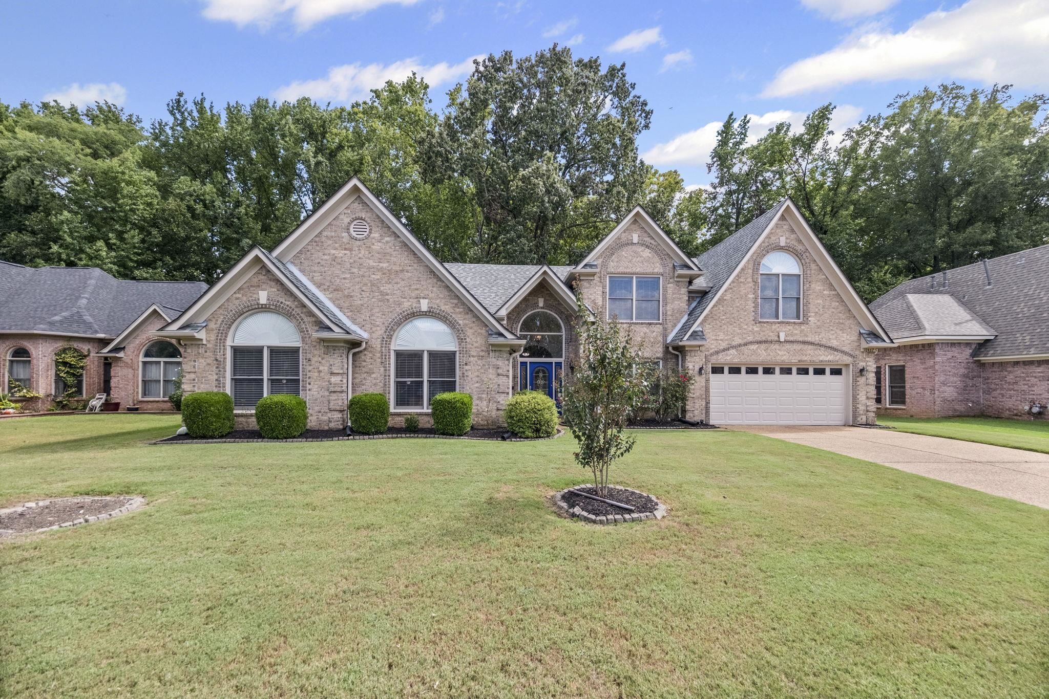 10467 Juneau Way Collierville, TN 38017 - Photo 1 of 34 a front view of a house with a garden and trees