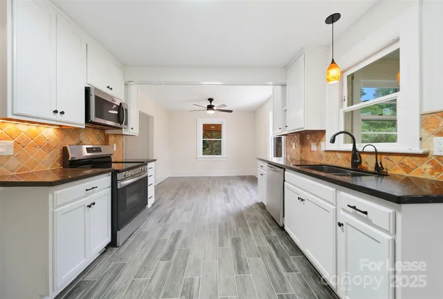 a kitchen with granite countertop a sink cabinets stainless steel appliances and a window