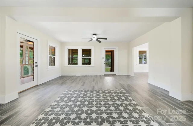 a view of an empty room with a window and wooden floor