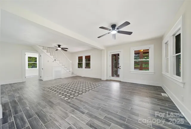 a view of an empty room with a window and wooden floor