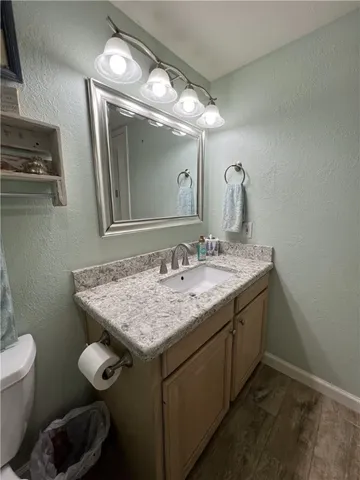a bathroom with a granite countertop sink a toilet and mirror