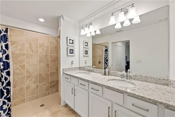 a bathroom with a granite countertop double vanity sink mirror and shower