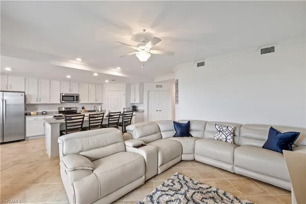 a living room with furniture kitchen view and a chandelier