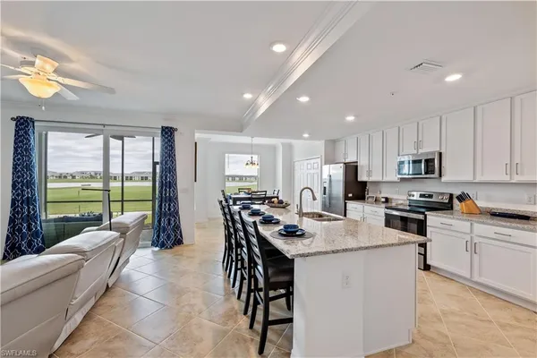 a kitchen with stainless steel appliances granite countertop a stove a refrigerator a kitchen island a couches and chairs with wooden floor