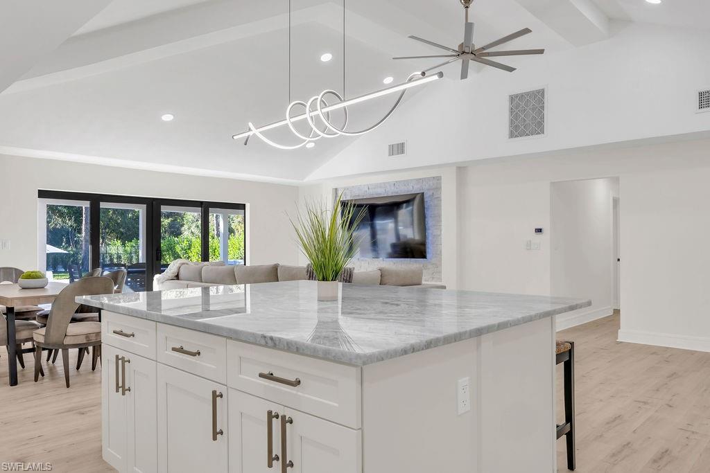 3155 64th Street Southwest Naples, FL 34105 - Photo 12 of 45 a kitchen with granite countertop a center island a dining table and chairs