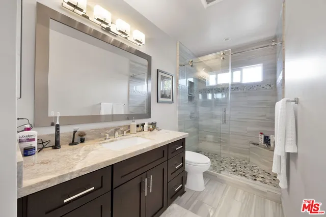 a bathroom with a sink a toilet a shower and a mirror