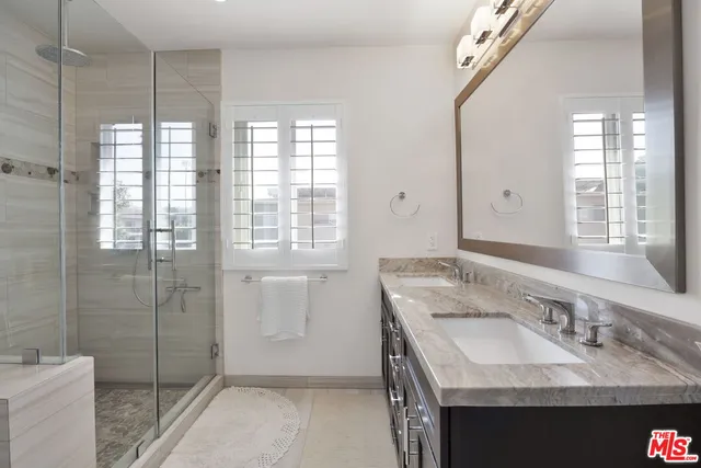 a bathroom with a granite countertop sink a mirror and a shower