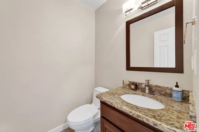 a bathroom with a granite countertop sink a toilet and a mirror