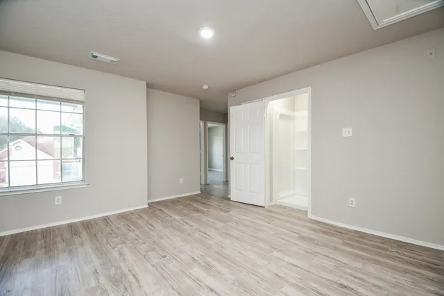 an empty room with wooden floor & windows and bathroom