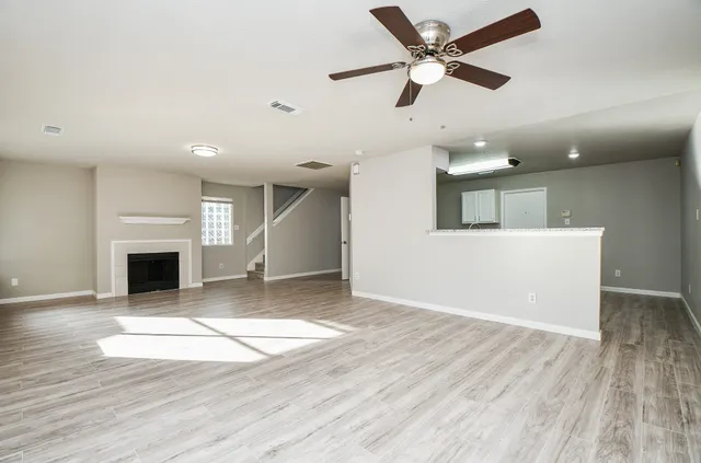 an empty room with wooden floor a fireplace and windows