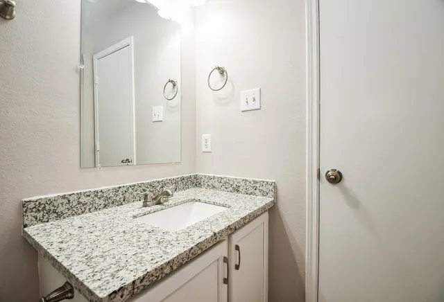 a bathroom with a granite countertop sink a toilet and bathtub