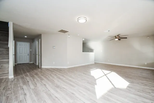 an empty room with wooden floor and windows