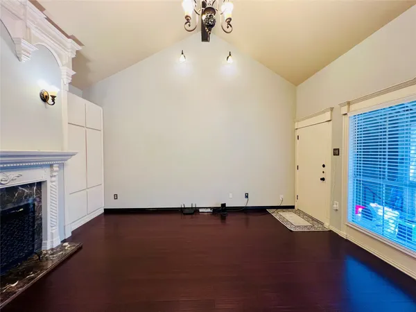 an empty room with wooden floor fireplace and windows