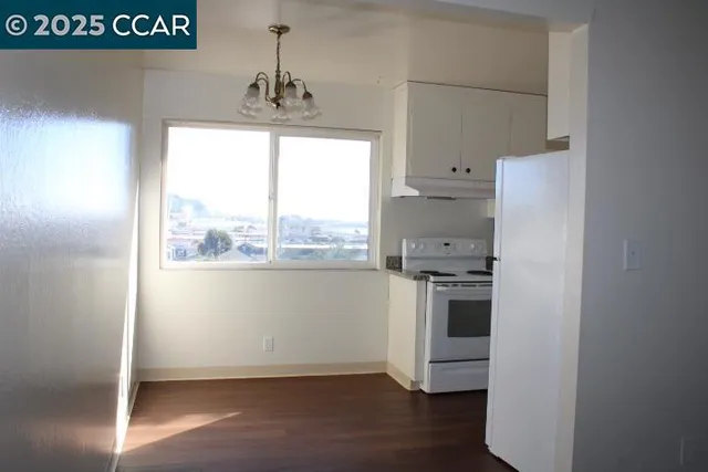 a kitchen with a refrigerator a stove top oven and wooden floor