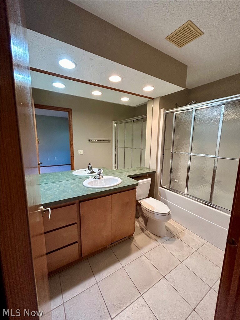 8763 Timber Edge Drive North Ridgeville, OH 44039 - Photo 26 of 40 Full bathroom with shower / bath combination with glass door, vanity with extensive cabinet space, toilet, tile floors, and a textured ceiling