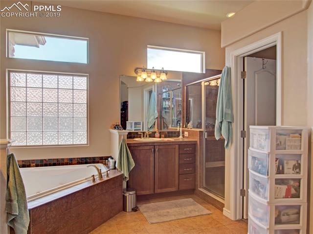 7644 Wichita Ridge Point Colorado Springs, CO 80923 - Photo 4 of 5 Large master bathroom has large jetted corner tub, two separate 42" vanities for him/her. Separate room with toilet. Large walk-in closet with window and stand alone shower.