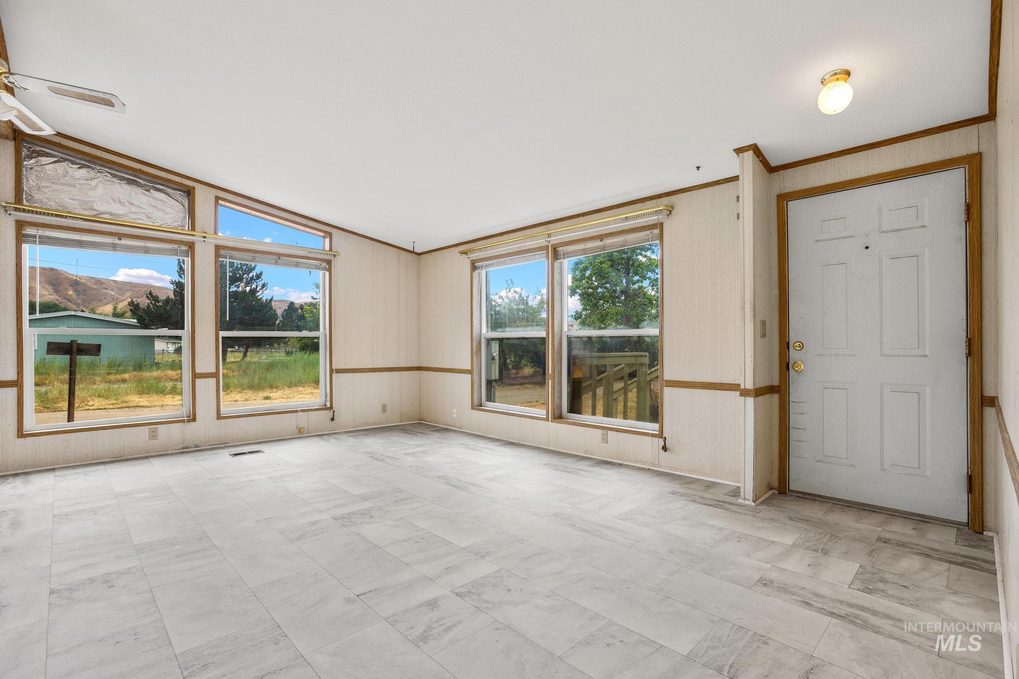 3680 South Mill Road Emmett, ID 83617 - Photo 9 of 38 Living area featuring wood-finish flooring, multiple large windows, a ceiling fan, and a front entry door with transom window