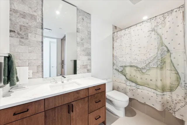 a bathroom with a granite countertop sink toilet mirror vanity and shower