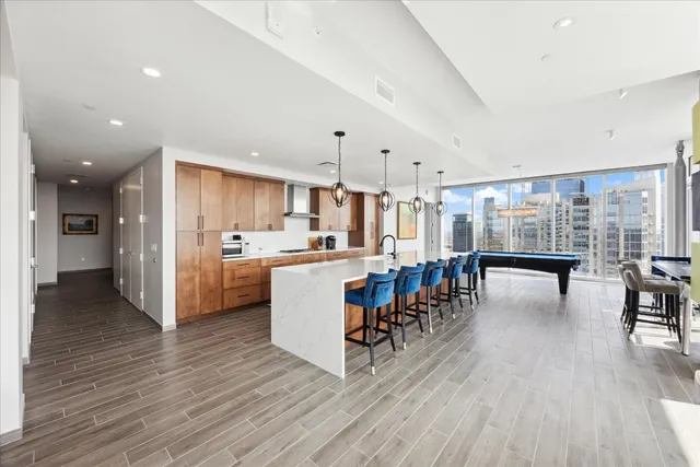 a living room with stainless steel appliances furniture wooden floor and a kitchen view