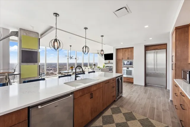 a large kitchen with stainless steel appliances kitchen island granite countertop a sink and a wooden floor
