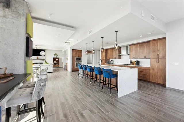 a kitchen with stainless steel appliances kitchen island granite countertop a table chairs and a refrigerator