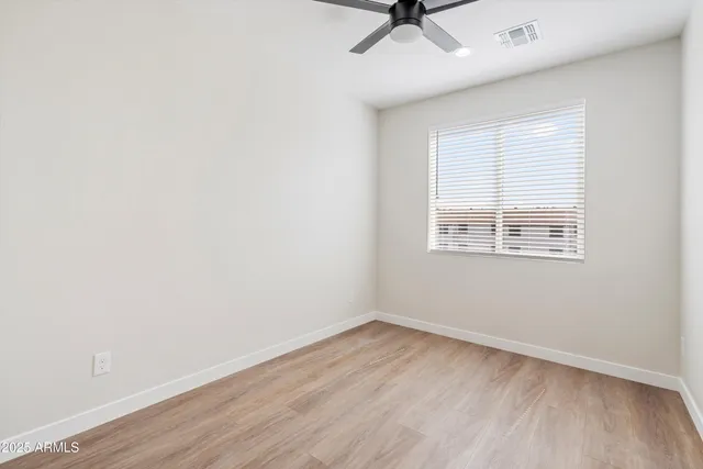 an empty room with a window and a ceiling fan