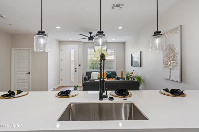 a view of a room with kitchen island stainless steel appliances sink refrigerator dining table and chairs