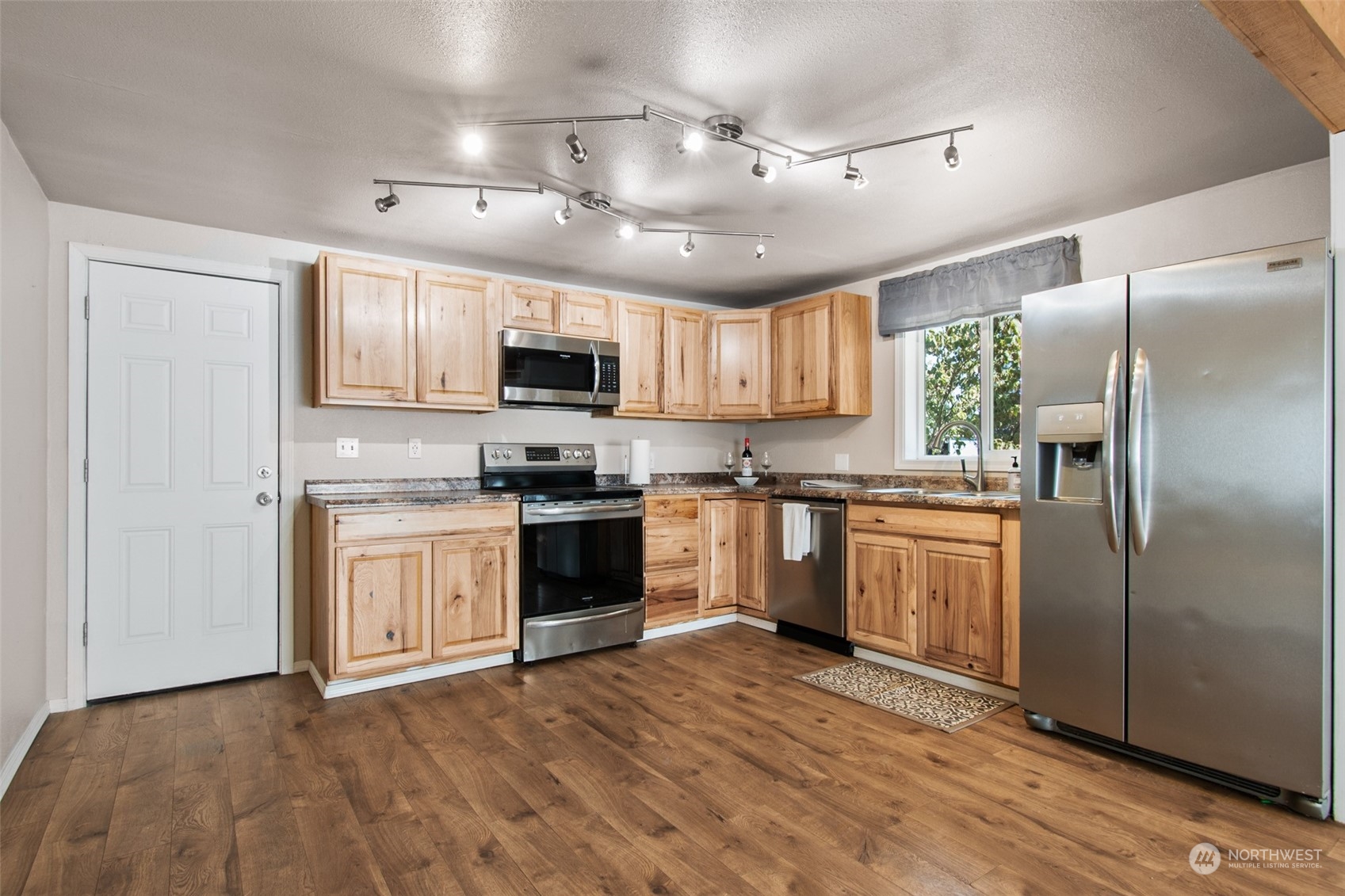 4840 176th Avenue Southwest Rochester, WA 98579 - Photo 9 of 38 a kitchen with kitchen island granite countertop a refrigerator a sink dishwasher a stove top oven a kitchen island and cabinets with wooden floor