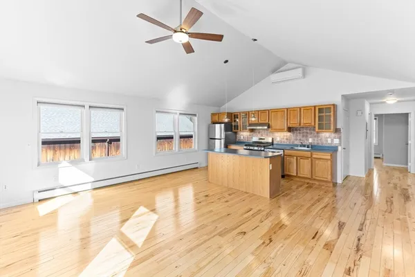 a living room with stainless steel appliances kitchen island granite countertop a stove and a sink