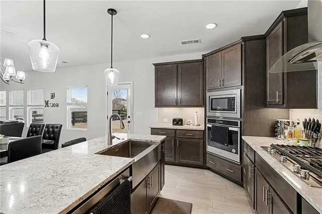 a kitchen with stainless steel appliances granite countertop a sink stove and refrigerator