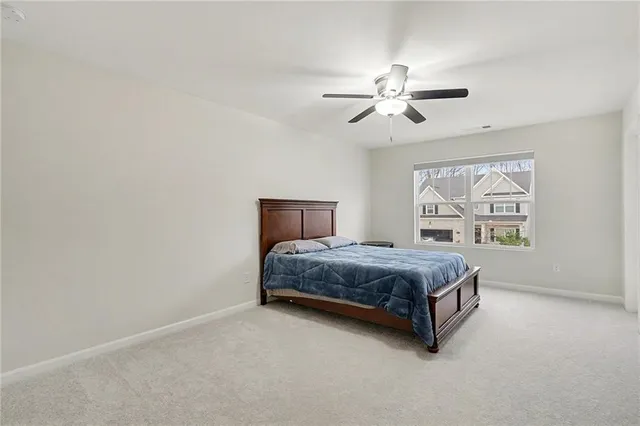 a spacious bedroom with a bed painting on wall and a large window