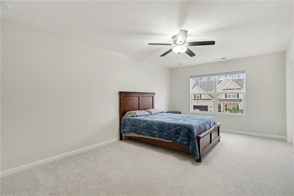 310 Coppergate Court Canton, GA 30115 - Photo 19 of 32 a spacious bedroom with a bed painting on wall and a large window