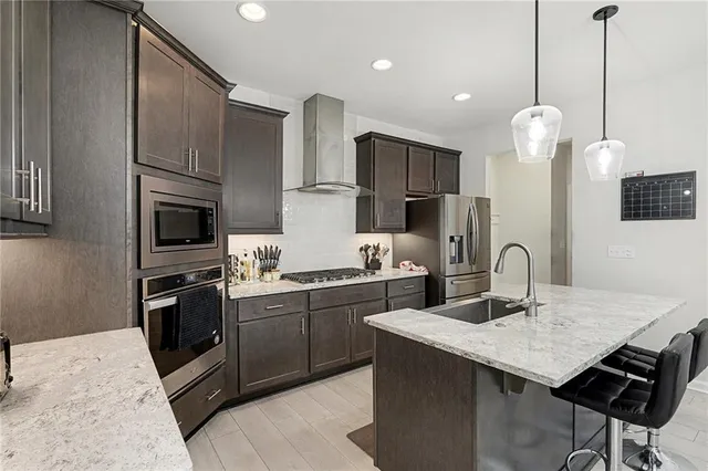 a kitchen with stainless steel appliances granite countertop a sink a stove a refrigerator and island
