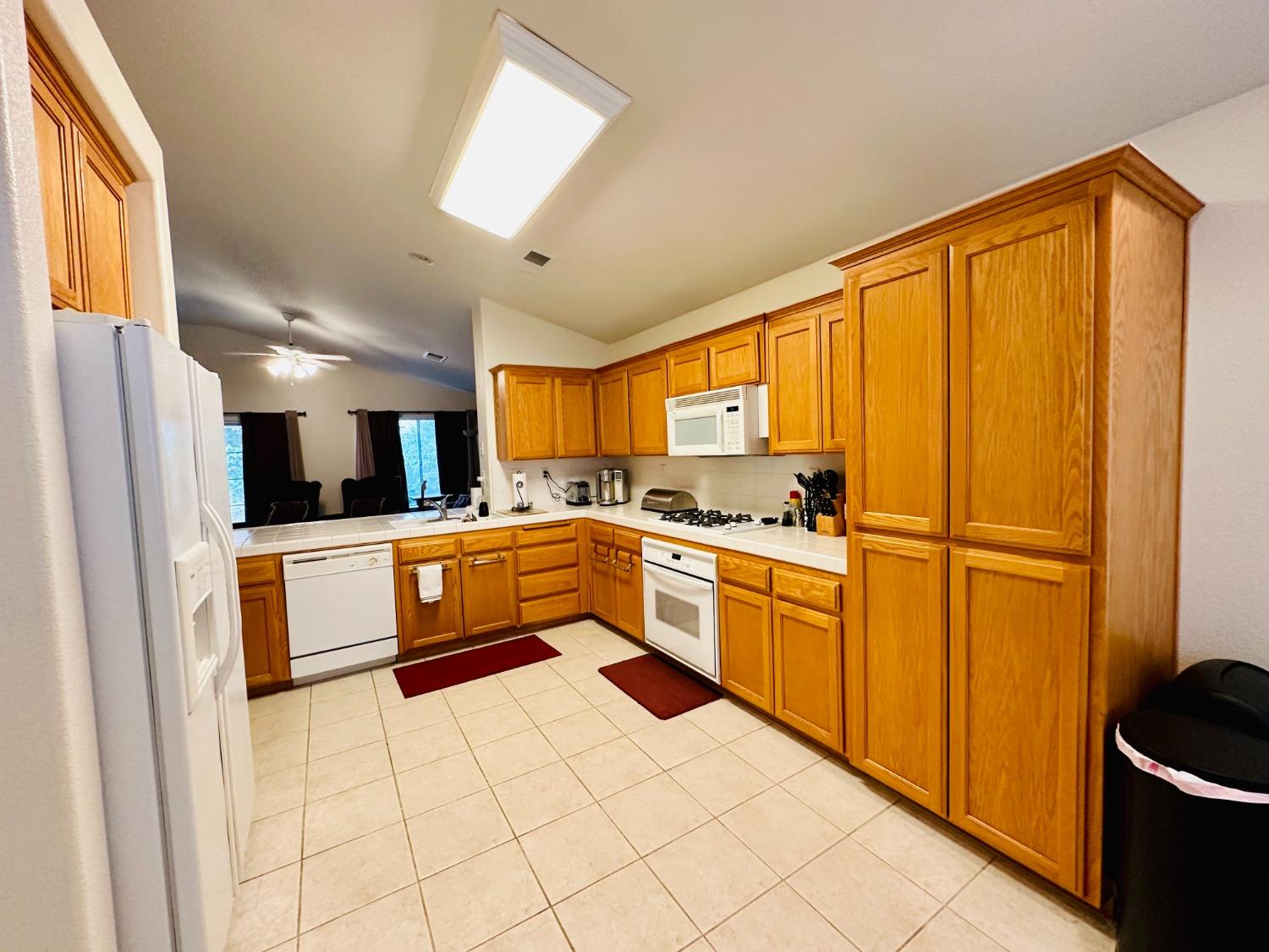 2439 Prescott Avenue Clovis, CA 93619 - Photo 5 of 25 a large kitchen with a refrigerator a sink dishwasher a stove and white cabinets with wooden floor