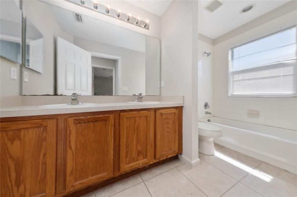 2962 White Cedar Circle Kissimmee, FL 34741 - Photo 17 of 24 a bathroom with a granite countertop sink mirror vanity and bathtub