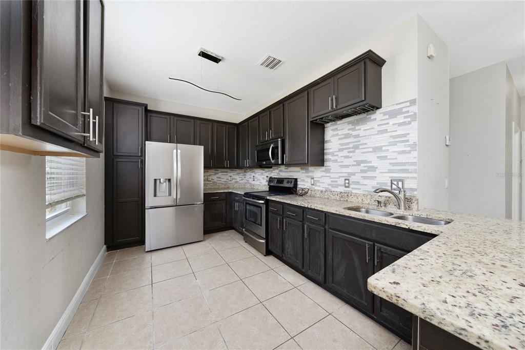 2962 White Cedar Circle Kissimmee, FL 34741 - Photo 7 of 24 a kitchen with stainless steel appliances granite countertop a sink stove refrigerator and cabinets