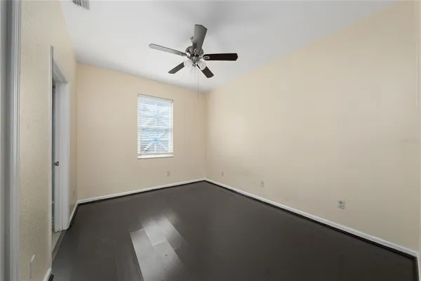 an empty room with wooden floor fan and windows