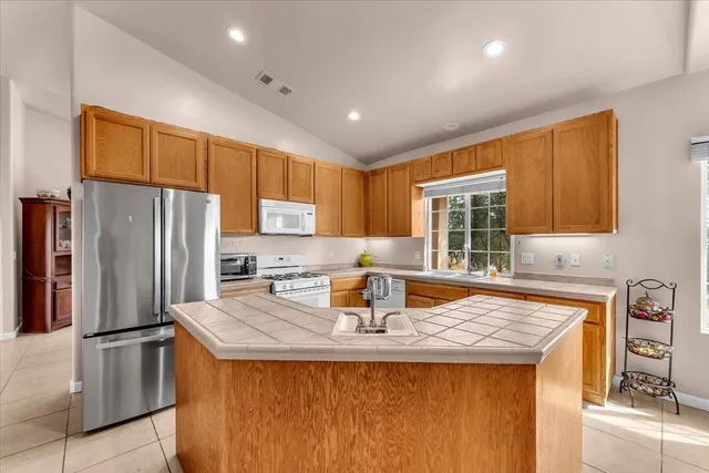a kitchen with stainless steel appliances granite countertop a sink refrigerator and cabinets