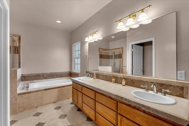 a bathroom with a granite countertop bathtub a double vanity sink and a mirror