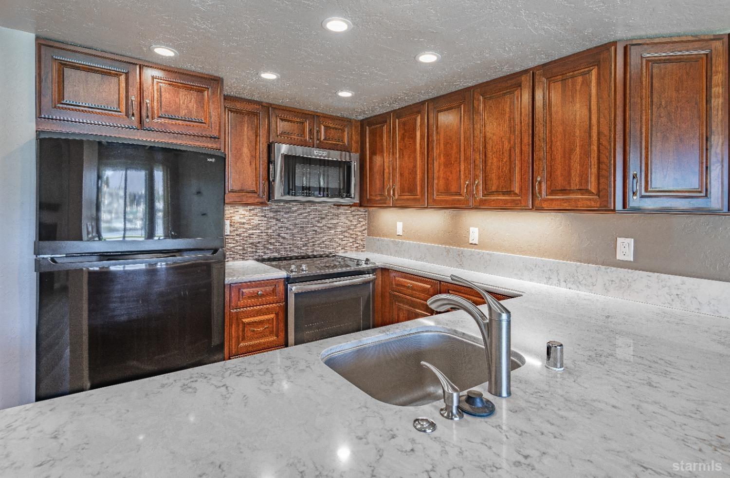 439 Ala Wai Boulevard, Unit 121 South Lake Tahoe, CA 96150 - Photo 7 of 35 a kitchen with granite countertop a refrigerator stove and cabinets