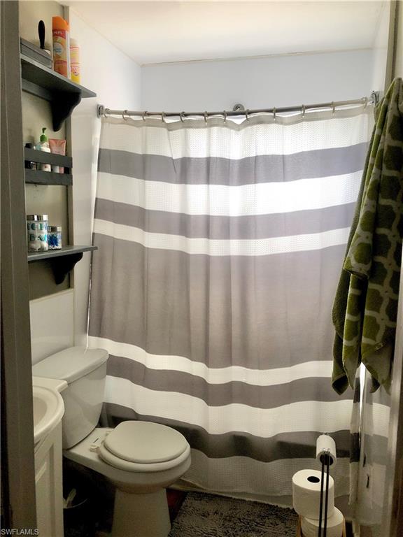 19 Massachusetts Road Lehigh Acres, FL 33936 - Photo 13 of 20 a bathroom with a toilet and a shower curtain