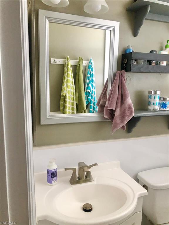 19 Massachusetts Road Lehigh Acres, FL 33936 - Photo 14 of 20 a bathroom with a sink a toilet and mirror
