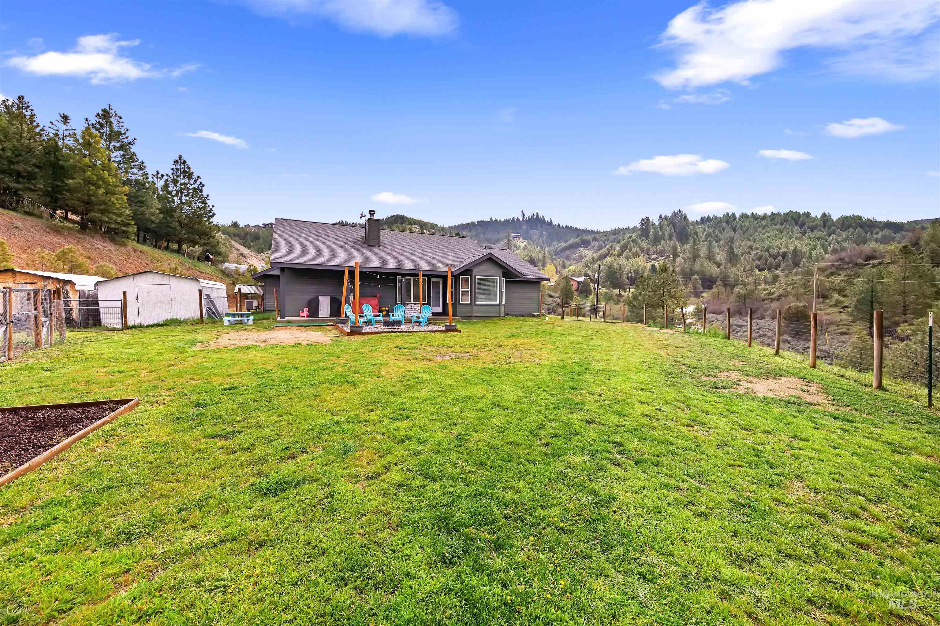4 Round Up Circle Boise, ID 83716 - Photo 41 of 47 Expansive property featuring a grey residence, a spacious lawn, a raised garden bed, and a fenced area