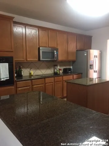 a kitchen with kitchen island granite countertop a sink window and cabinets