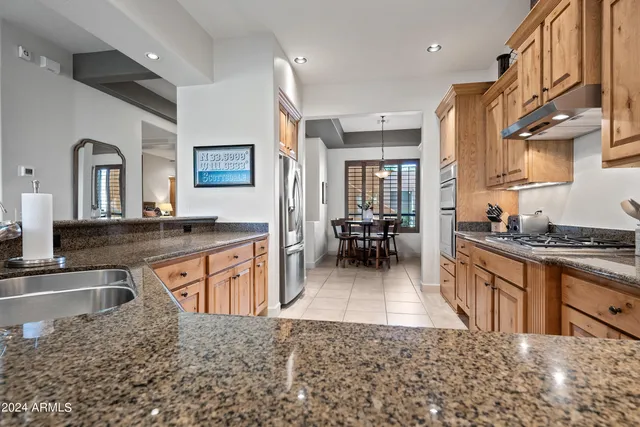 a large kitchen with stainless steel appliances granite countertop a large stove top oven a refrigerator a sink and dishwasher