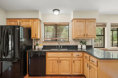 a kitchen with granite countertop a sink stove and refrigerator