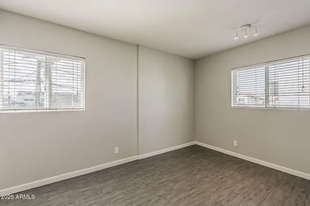 an empty room with wooden floor and windows