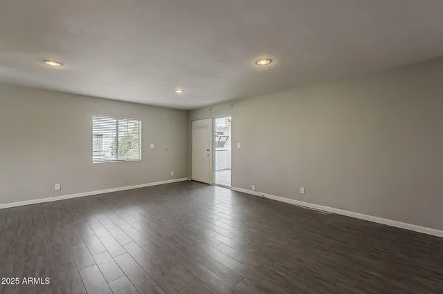 a view of an empty room and a window with wooden floor