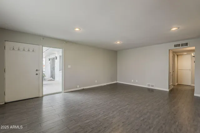a view of an empty room with wooden floor and closet
